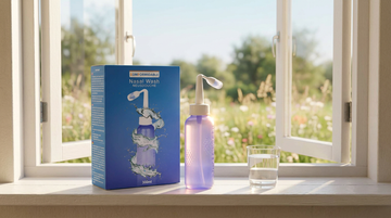 Comformidable Nasendusche mit Spülsalz auf einer sonnigen Fensterbank, blühende Sommerwiese im Hintergrund