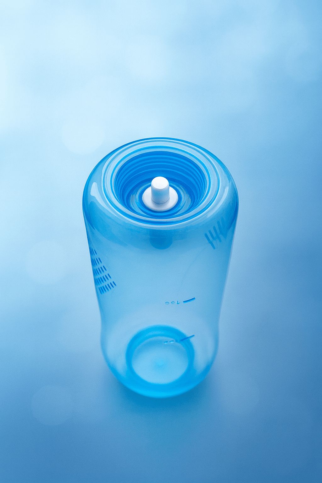 Draufsicht einer transparenten blauen Nasenduschflasche mit weißem Druckknopf für die einfache Bedienung.